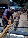 Man scraping old varnish from mast