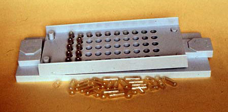 A small and cheap device for manually filling small quantities of hard gelatin capsules.