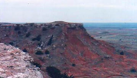 The red shale composition of one of the buttes of the Glass Mountain Chain in Western Oklahoma provides a stark contrast to the muted blues and greens of the vista beyond.